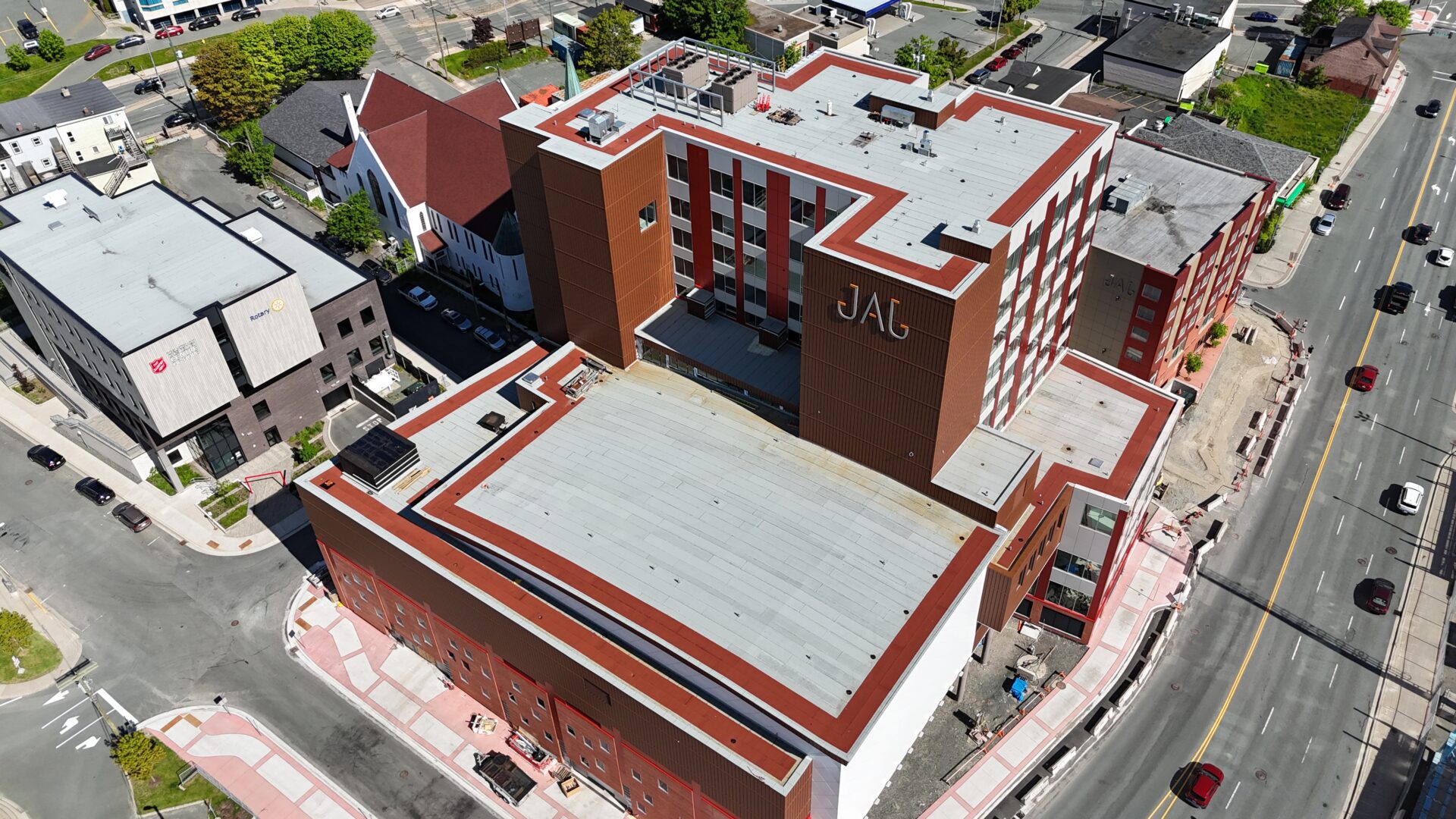 Aerial view of a multi-story building with "JAG" on the facade, featuring red and white vertical stripes
